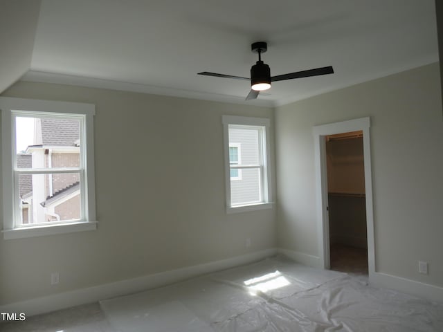 unfurnished bedroom with baseboards, a walk in closet, and ceiling fan