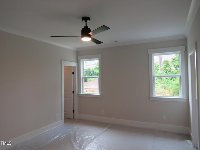 spare room with baseboards, crown molding, and a ceiling fan