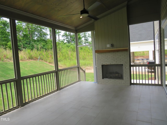 unfurnished sunroom with ceiling fan, lofted ceiling, a fireplace, and plenty of natural light
