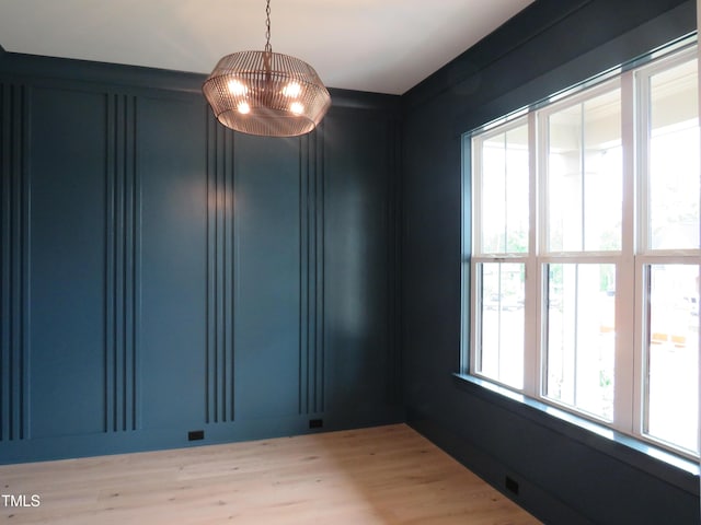 unfurnished room featuring light wood finished floors and a chandelier