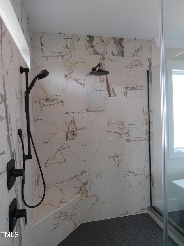 full bathroom with a tile shower and plenty of natural light