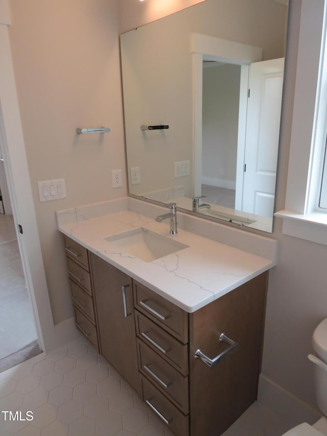 bathroom featuring toilet, vanity, tile patterned floors, and baseboards