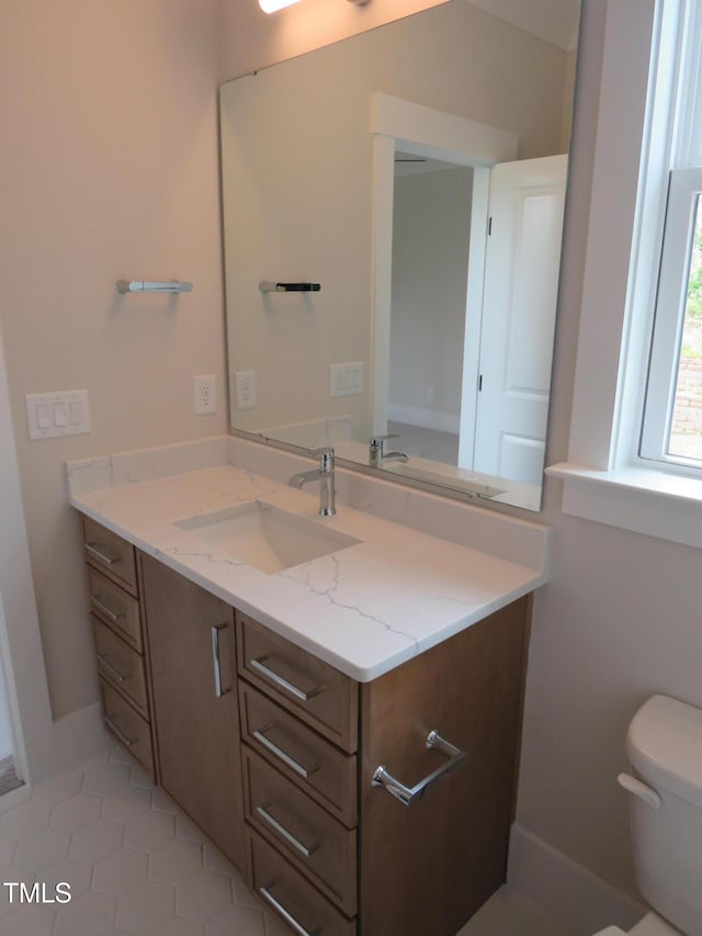 half bathroom with toilet, vanity, baseboards, and tile patterned flooring