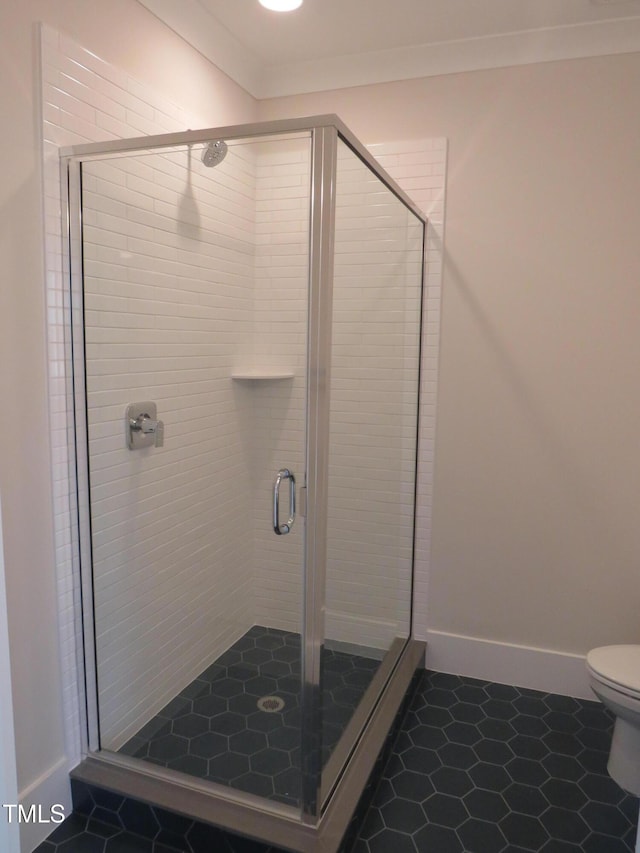 full bath featuring a stall shower, toilet, and baseboards