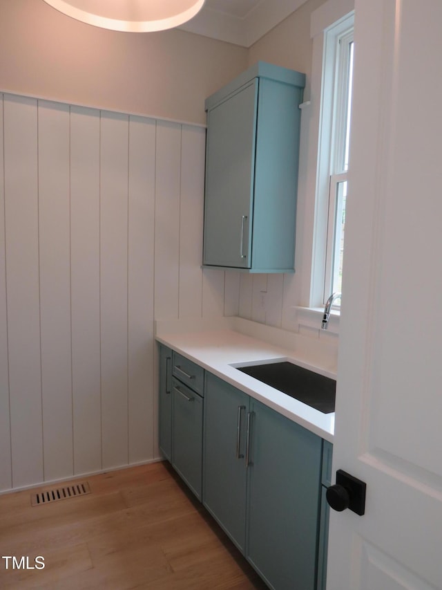 kitchen featuring a sink, light wood-type flooring, light countertops, and gray cabinetry