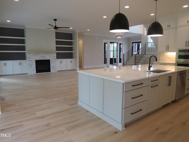 kitchen featuring a sink, a ceiling fan, stainless steel appliances, ornamental molding, and light wood-type flooring