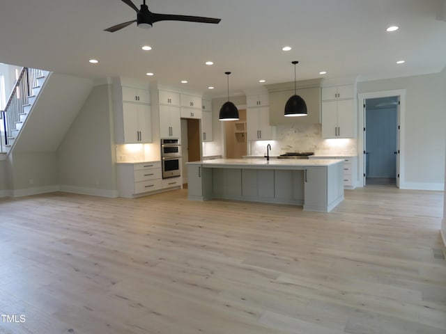 kitchen with double oven, white cabinetry, backsplash, a ceiling fan, and baseboards