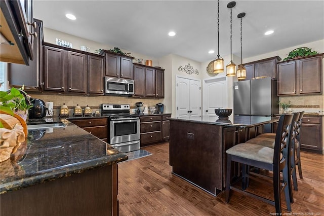 kitchen featuring stainless steel appliances, dark brown cabinets, backsplash, dark wood finished floors, and recessed lighting