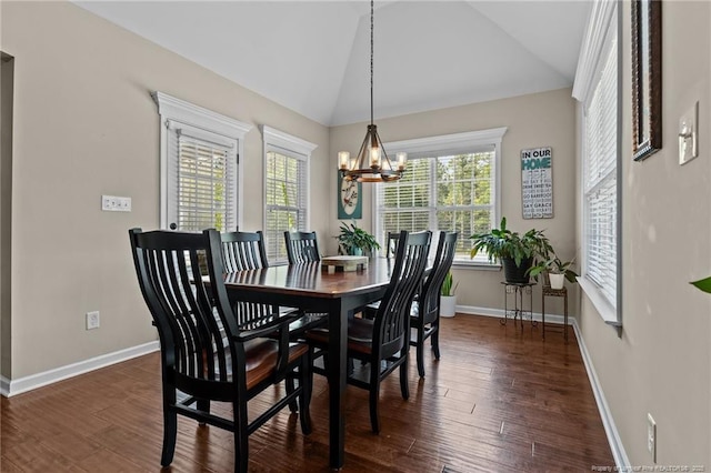 dining area featuring a chandelier, healthy amount of natural light, vaulted ceiling, baseboards, and wood finished floors