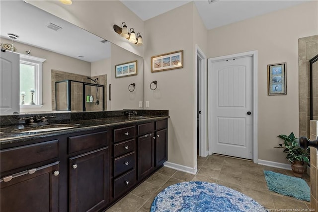 full bath with a stall shower, double vanity, baseboards, and tile patterned floors