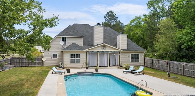 back of property with a patio, a chimney, and a shingled roof