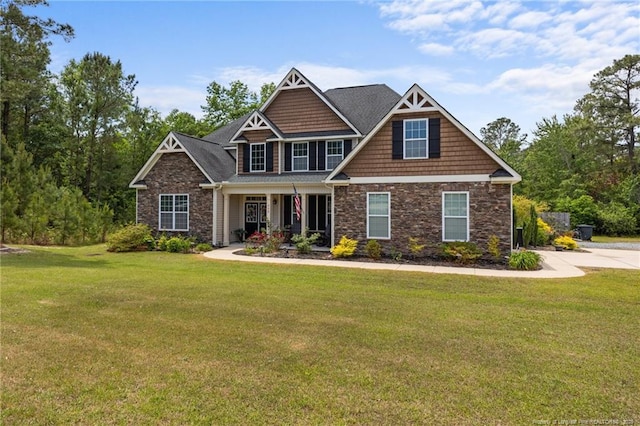 craftsman-style house with stone siding, a front lawn, and covered porch
