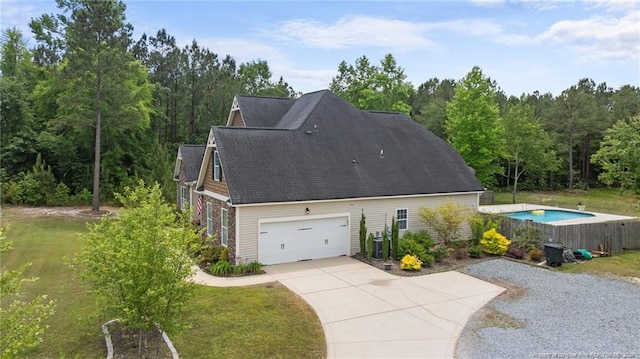 view of home's exterior featuring concrete driveway, a yard, and roof with shingles
