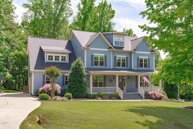 craftsman house with covered porch, board and batten siding, a front yard, and concrete driveway