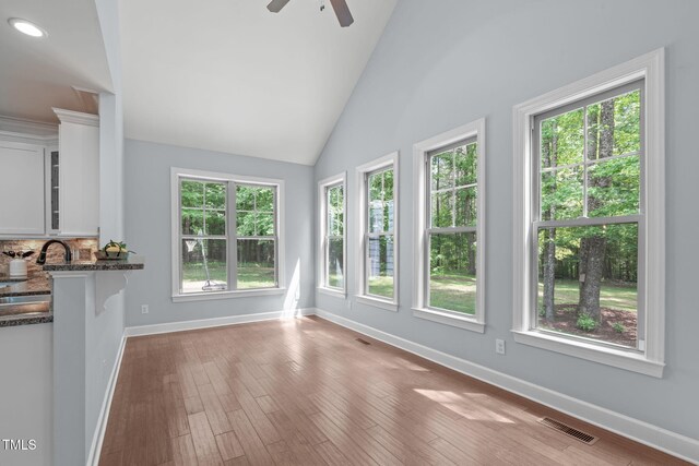 unfurnished living room featuring ceiling fan, baseboards, wood-type flooring, and vaulted ceiling