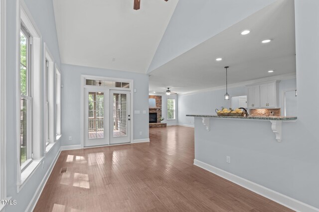 unfurnished living room with a ceiling fan, plenty of natural light, baseboards, vaulted ceiling, and recessed lighting