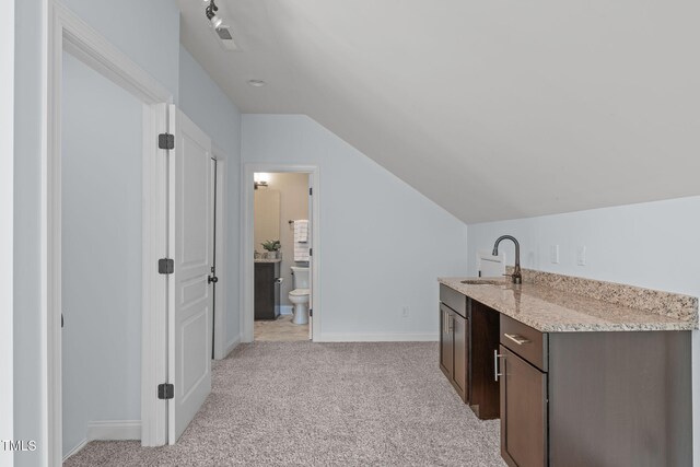 indoor wet bar featuring light carpet, vaulted ceiling, and baseboards