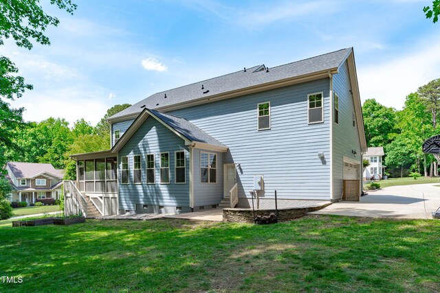 back of property with a sunroom, a lawn, concrete driveway, and stairs