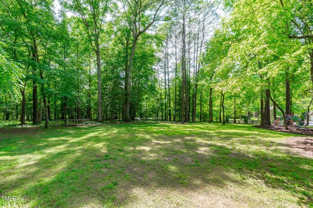 view of grassy yard featuring a view of trees