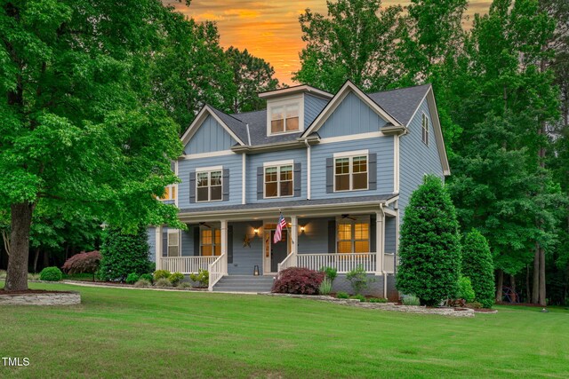 view of front of home featuring a porch, a front lawn, and board and batten siding