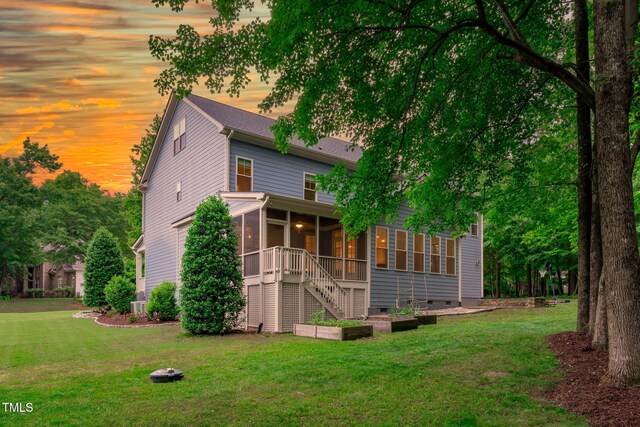 rear view of property with a sunroom, a lawn, stairs, and crawl space