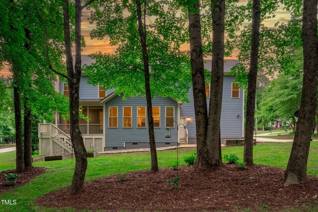 view of front facade featuring crawl space, stairway, a lawn, and a shingled roof