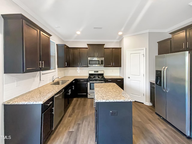 kitchen with a sink, stainless steel appliances, tasteful backsplash, ornamental molding, and a center island