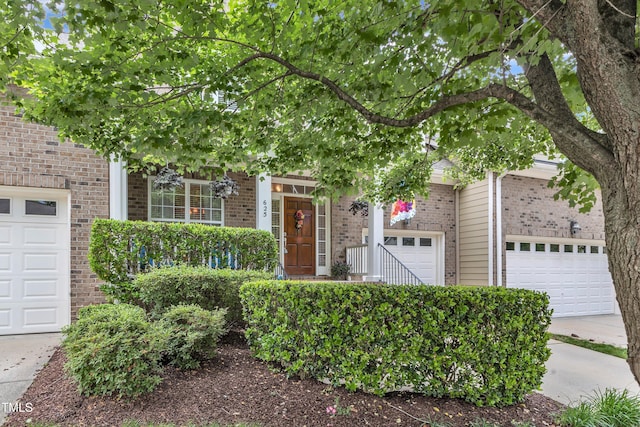 obstructed view of property featuring a garage, brick siding, and concrete driveway