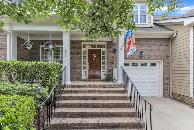 view of exterior entry featuring concrete driveway, a garage, brick siding, and roof with shingles