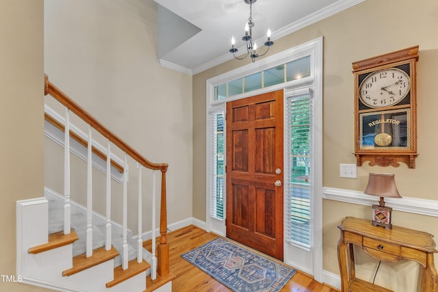 entryway featuring wood finished floors, crown molding, stairway, a chandelier, and baseboards