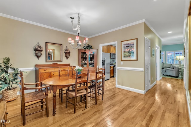 dining space featuring ornamental molding, a chandelier, light wood finished floors, and baseboards