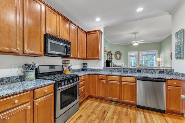 kitchen featuring appliances with stainless steel finishes, a sink, brown cabinetry, crown molding, and recessed lighting