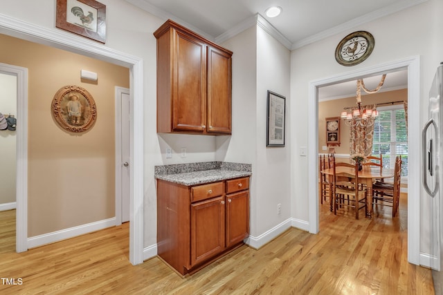hallway featuring a chandelier, light wood finished floors, ornamental molding, and baseboards