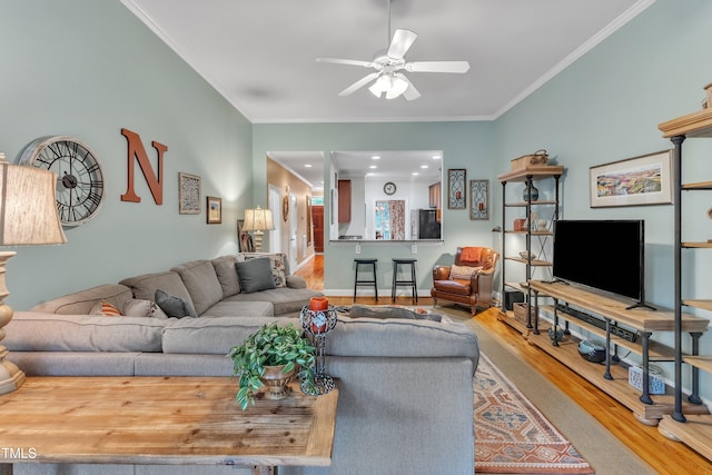 living room with wood finished floors, ceiling fan, ornamental molding, and baseboards