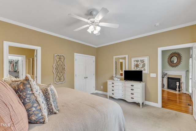 bedroom with crown molding, baseboards, a closet, a fireplace with flush hearth, and light carpet