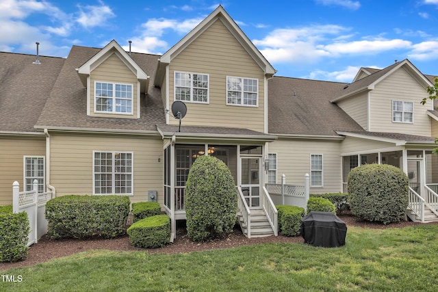 view of front of house featuring a sunroom, roof with shingles, and a front lawn
