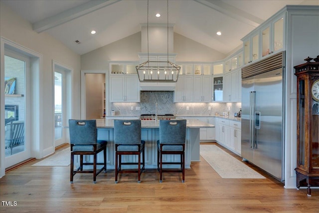 76 Soundside Dr, Oriental, NC 28571 - kitchen featuring stainless steel built in refrigerator, a kitchen island with sink, white cabinetry, backsplash, and beam ceiling