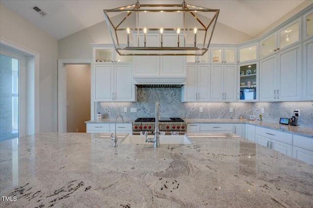 76 Soundside Dr, Oriental, NC 28571 - kitchen with lofted ceiling, backsplash, light stone countertops, and white cabinetry