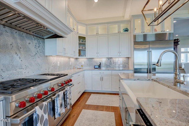 76 Soundside Dr, Oriental, NC 28571 - kitchen with high end appliances, custom range hood, light wood finished floors, a sink, and white cabinetry