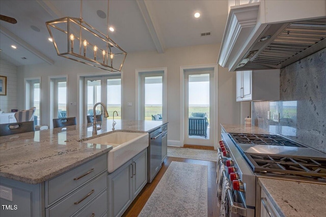 76 Soundside Dr, Oriental, NC 28571 - kitchen featuring appliances with stainless steel finishes, a sink, under cabinet range hood, light stone counters, and wood finished floors