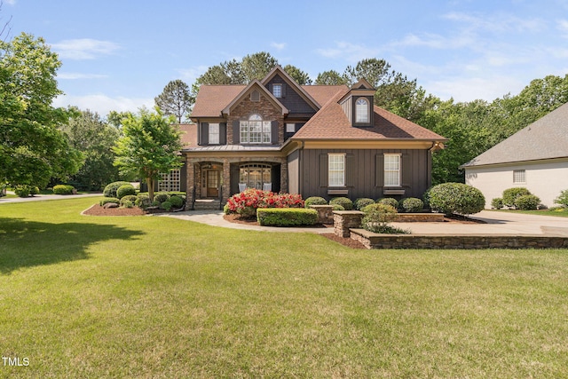 craftsman inspired home with board and batten siding, a front yard, a shingled roof, and a porch