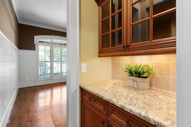 bar area with tasteful backsplash, wood finished floors, crown molding, wainscoting, and baseboards