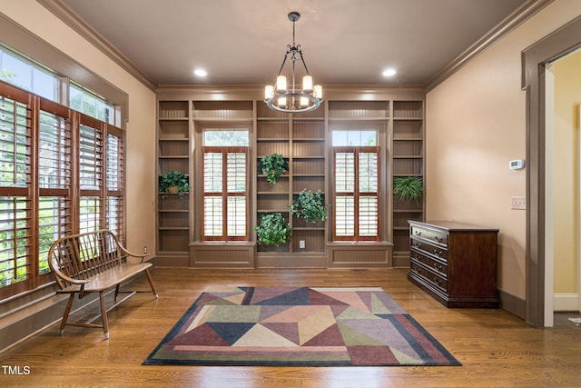 living area featuring crown molding, a chandelier, built in features, baseboards, and wood finished floors