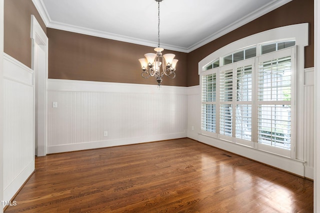 spare room with a wainscoted wall, a chandelier, plenty of natural light, wood finished floors, and crown molding