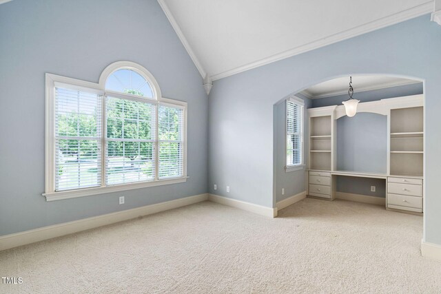 carpeted spare room with crown molding, plenty of natural light, lofted ceiling, baseboards, and arched walkways