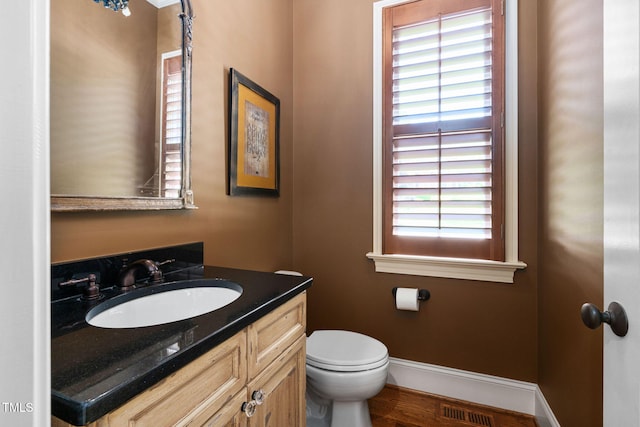 bathroom featuring toilet, vanity, baseboards, and wood finished floors