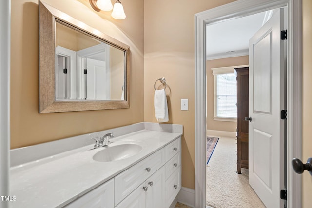 bathroom with vanity, crown molding, and baseboards