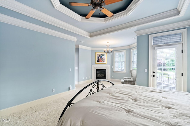 bedroom featuring carpet flooring, a tray ceiling, access to exterior, a chandelier, and ornamental molding