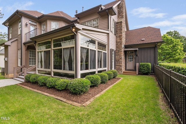 back of property with a shingled roof, a chimney, entry steps, and a balcony