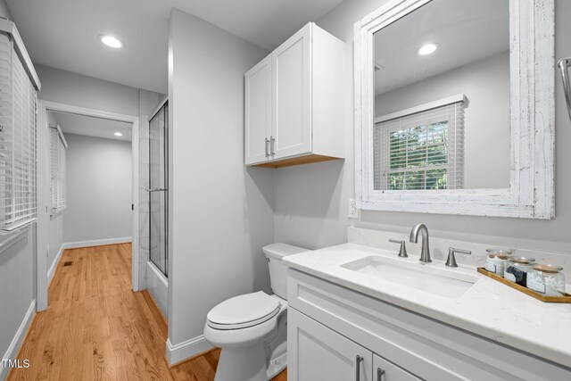 5208 Melbourne Rd, Raleigh, NC 27606 - bathroom with toilet, wood finished floors, vanity, recessed lighting, and bath / shower combo with glass door